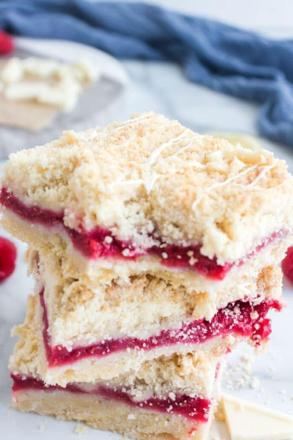 a bite taken out of the top Raspberry Crumble Bar that is on a stack of bars on marble counter