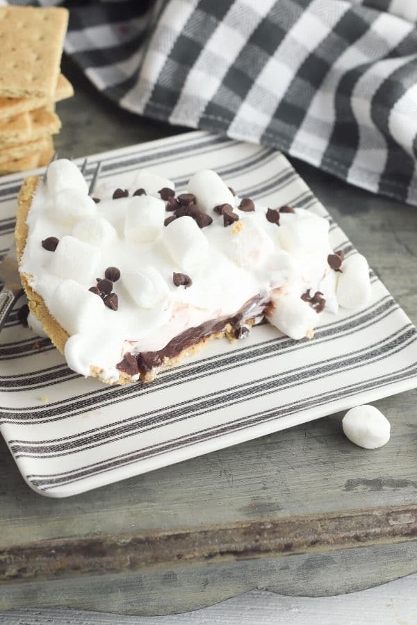 s'mores pie slice on a plate with black and white towel behind