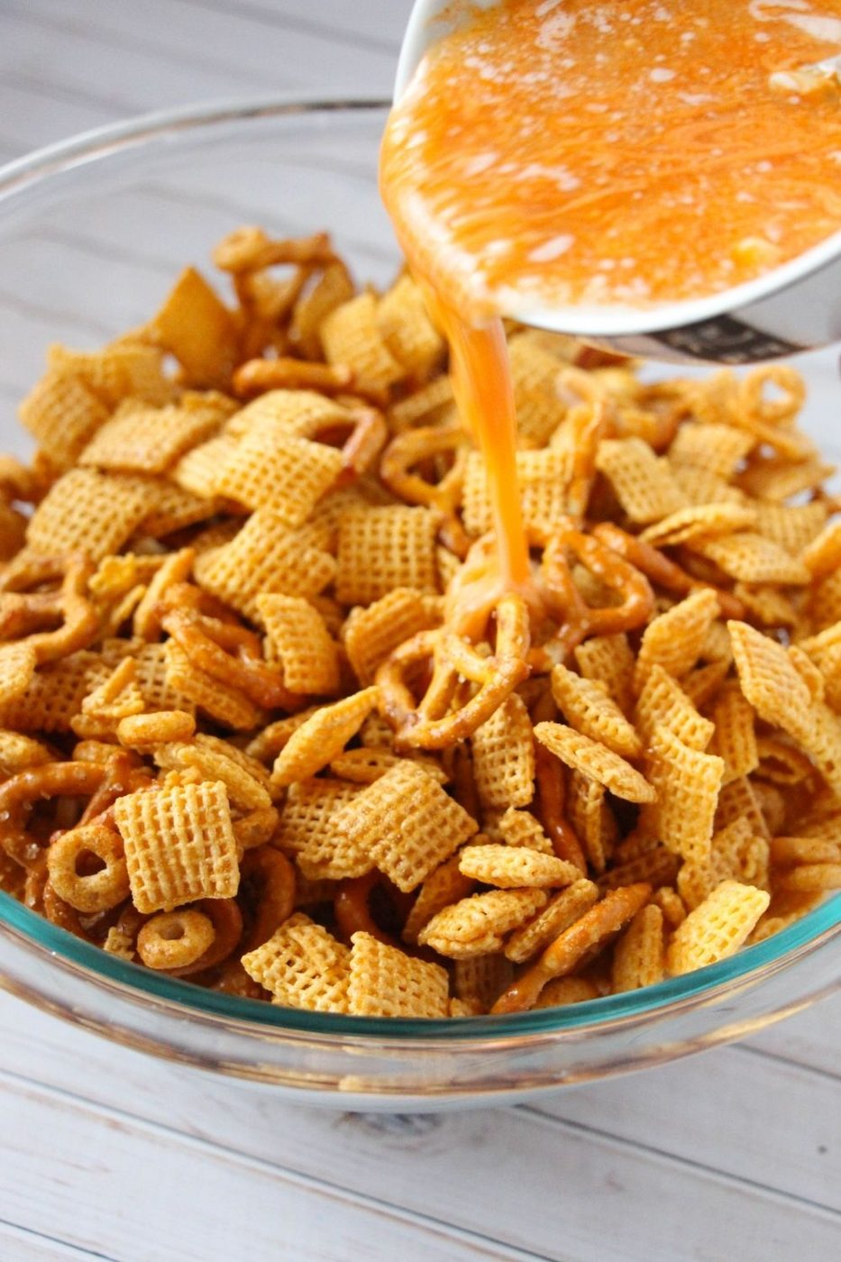 pouring butter and hot sauce on Chex mix