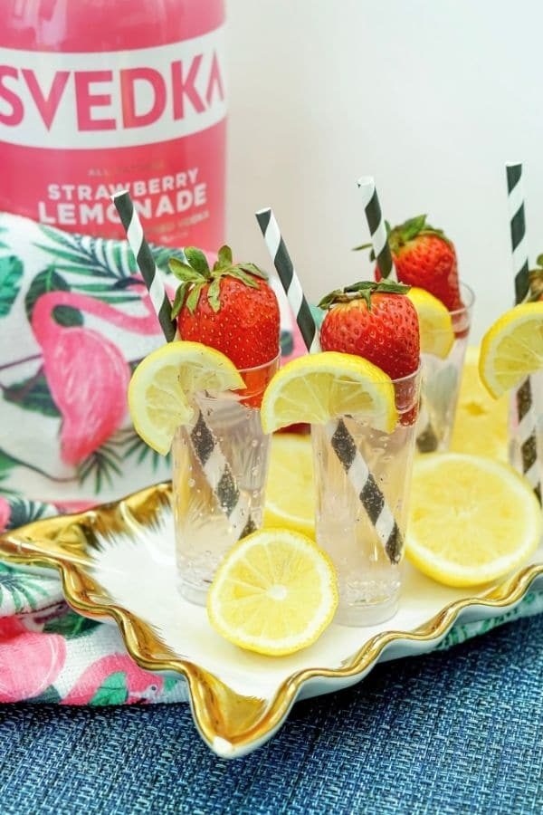summer cocktails on a serving platter with vodka behind it