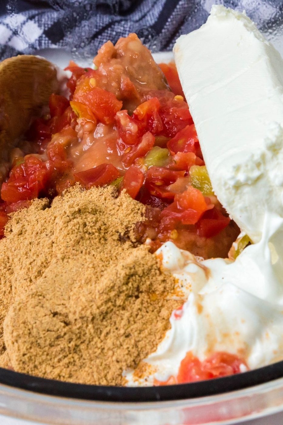 ingredients for cream cheese bean dip in a bowl with towel behind it 