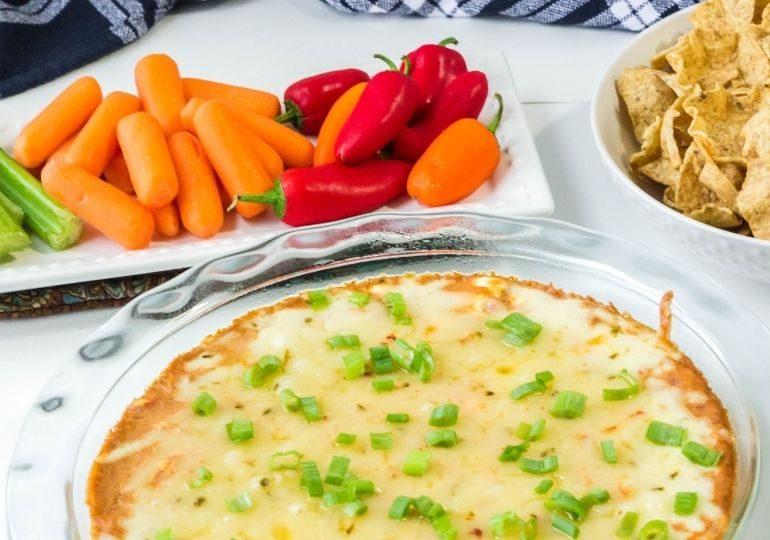 texas trash dip in a pan with veggies and chips around it
