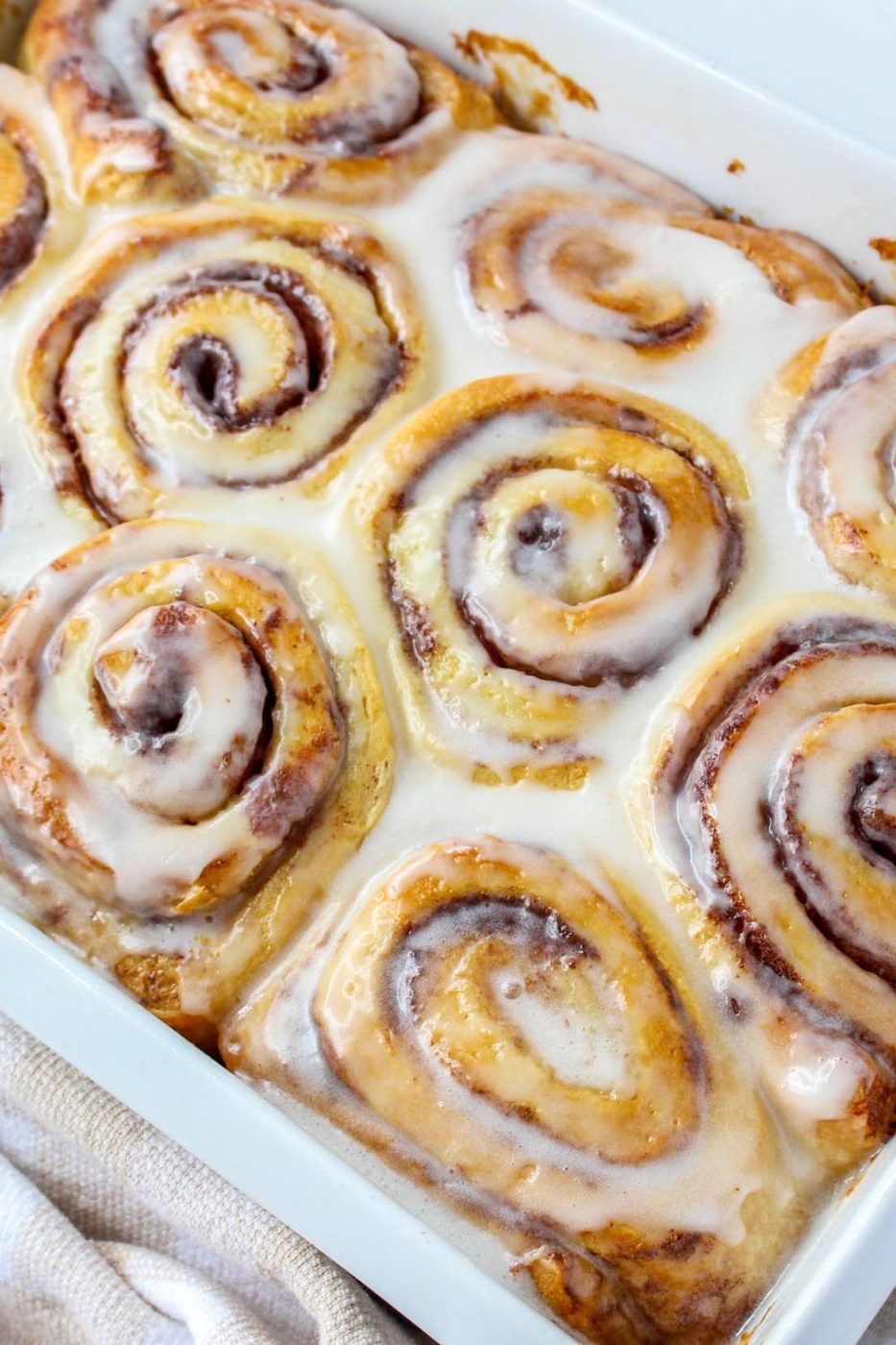 cinnamon rolls baked and frosting in a baking dish 