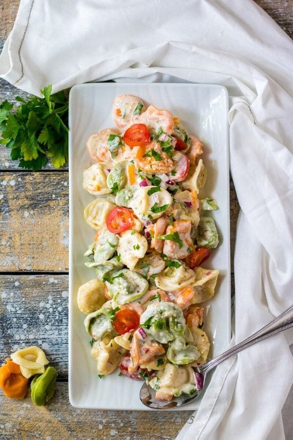 tortellini salad on a serving tray with towel by it
