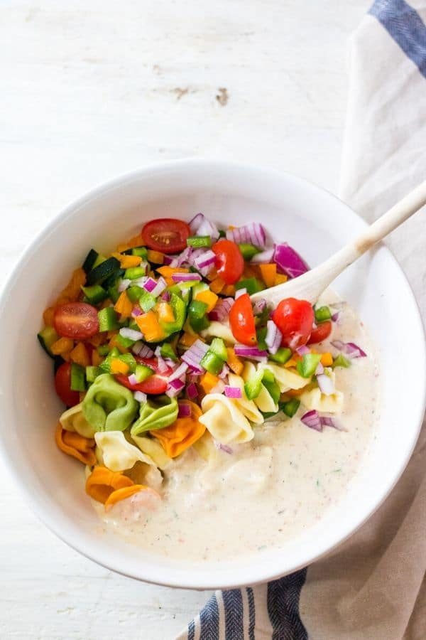 pasta and sauce in a white bowl with spoon by it