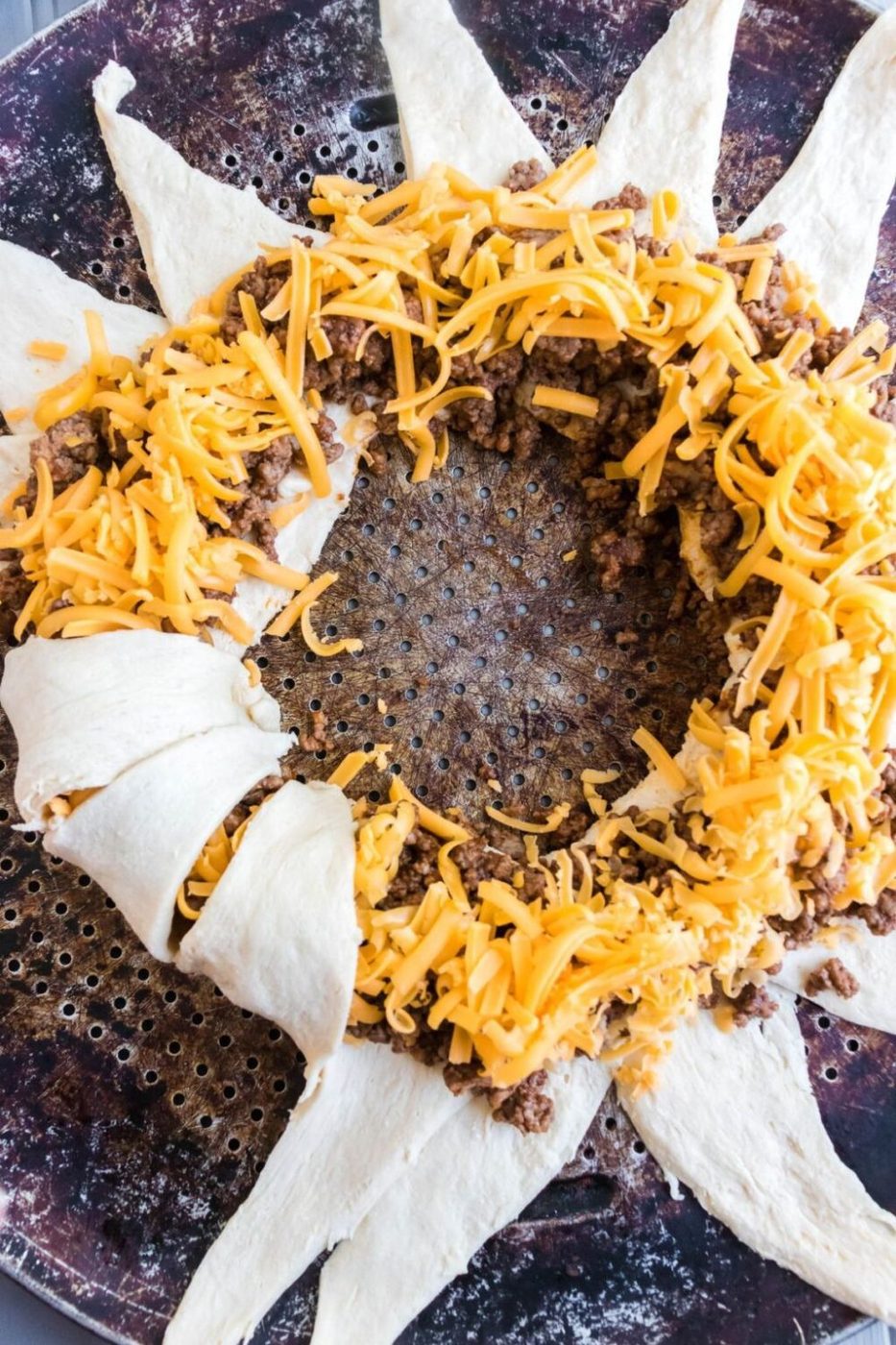 folding up a crescent roll taco ring on a baking sheet 