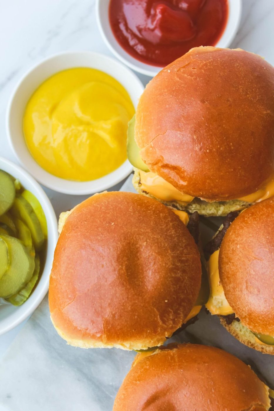 burger sliders on plate with mustard, ketchup and pickles