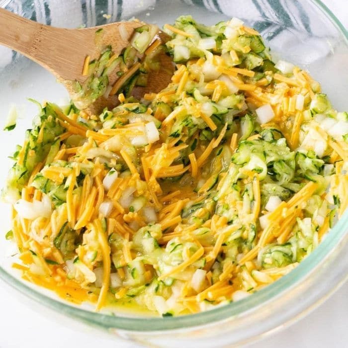 zucchini mixture with cheese in a bowl with a wooden spoon in bowl 