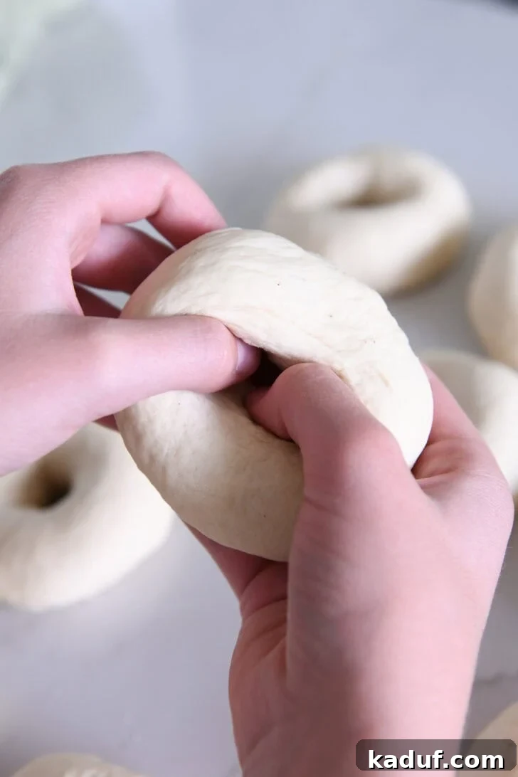 The Ultimate Homemade Bagel Recipe 6 Pressing thumbs into dough ball to form bagel.