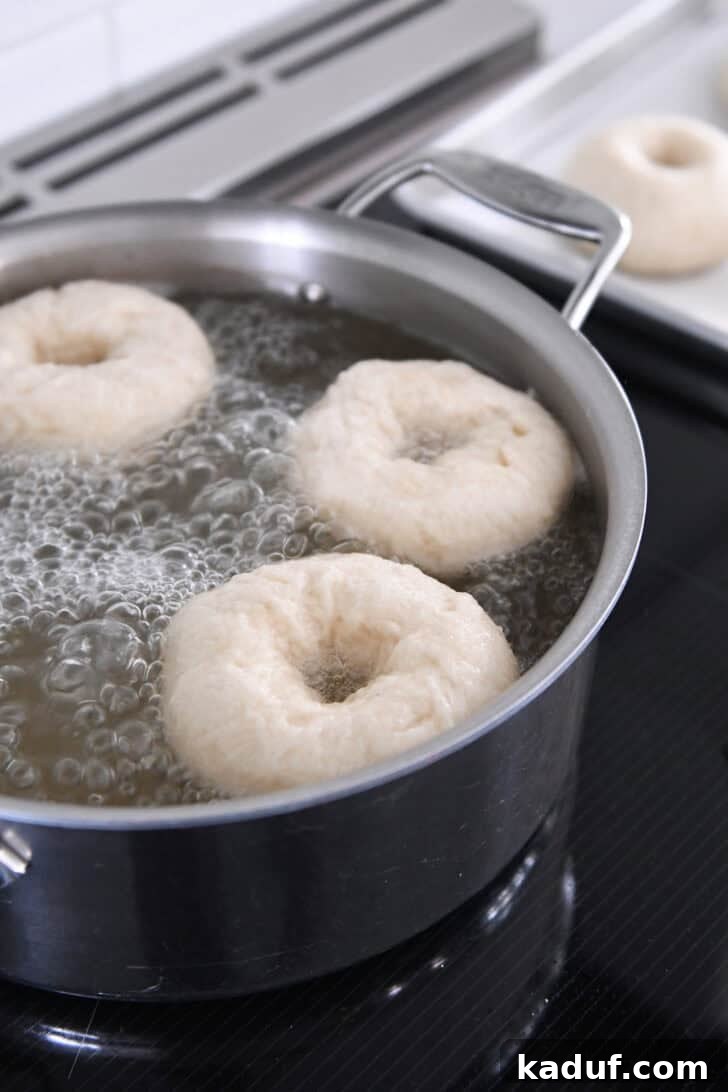 The Ultimate Homemade Bagel Recipe 8 Boiling bagels in water bath with honey.