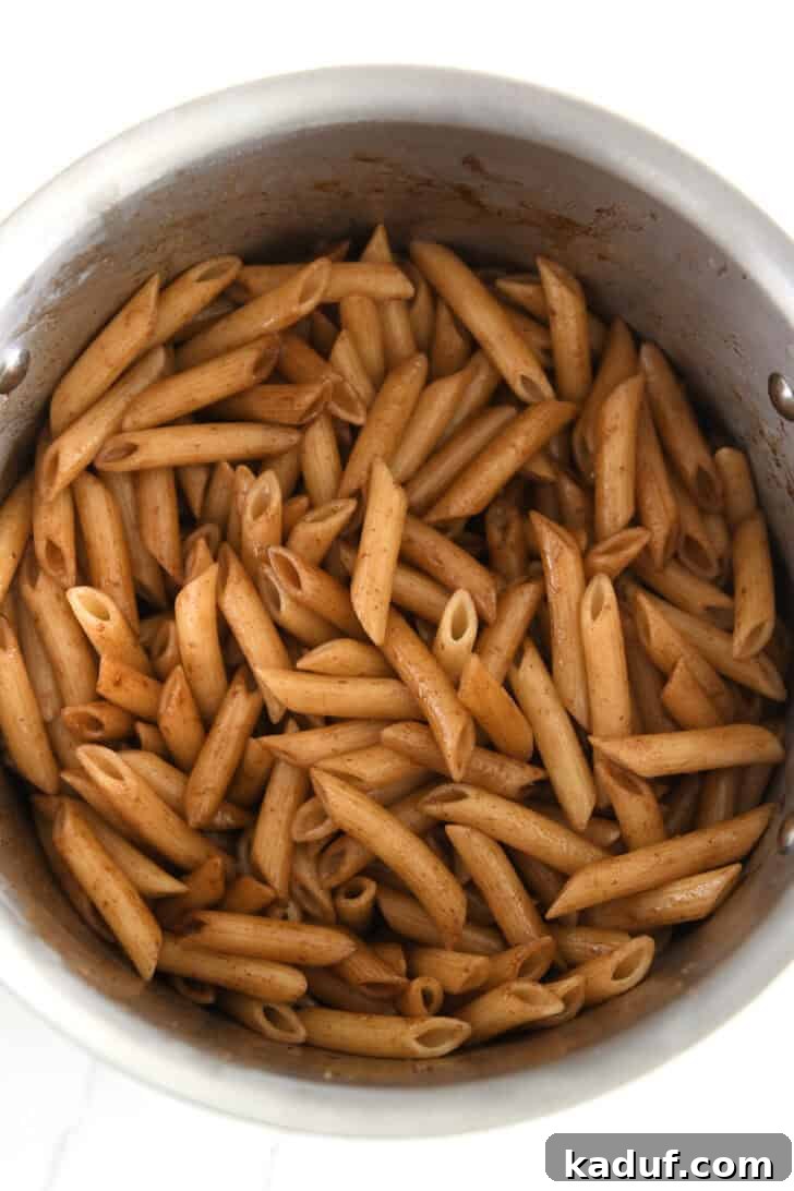A stainless pot containing penne pasta coated with the exquisite balsamic brown butter sauce.