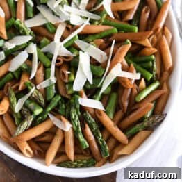 White serving dish with balsamic penne pasta, Parmesan cheese, and roasted asparagus.