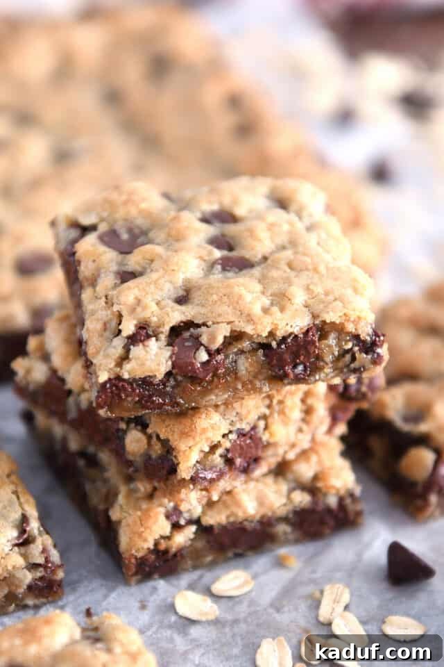 Golden Oat Chocolate Chip Squares 2 Three stacked square oatmeal chocolate chip cookie bars, showcasing their soft texture and abundant chocolate chips.