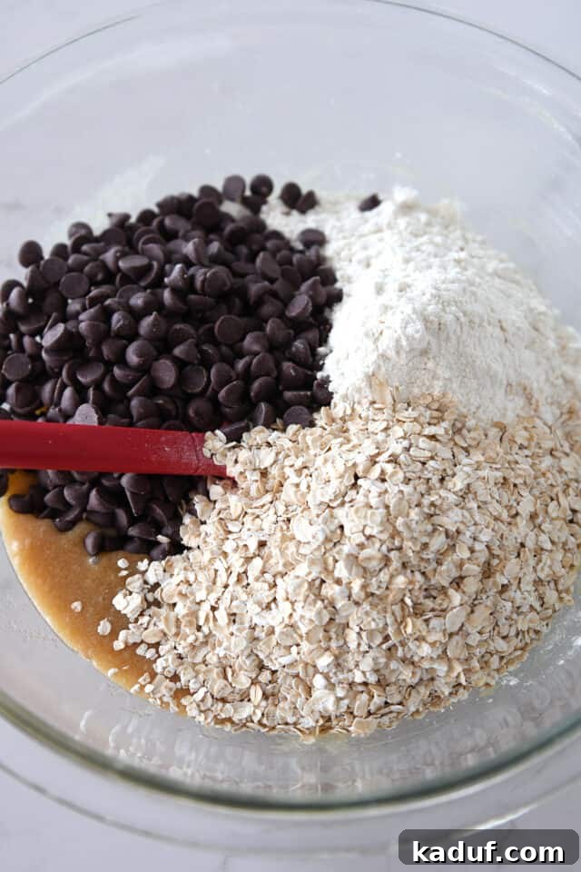 Golden Oat Chocolate Chip Squares 4 Glass bowl with chocolate chips, flour, and oatmeal, representing the dry ingredients for the cookie bars.