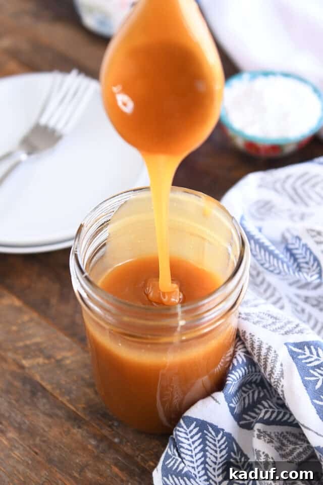 Sweet Tangy Buttermilk Caramel 7 Wooden spoon drizzling caramel syrup into glass jar.