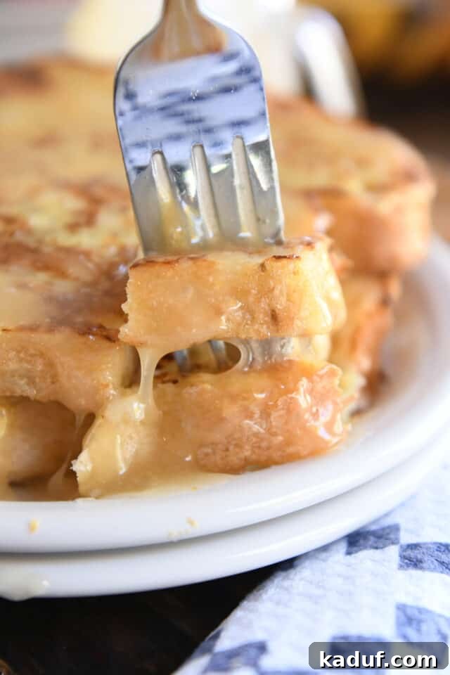 Sweet Tangy Buttermilk Caramel 9 Fork piercing two pieces of French toast on white plate.