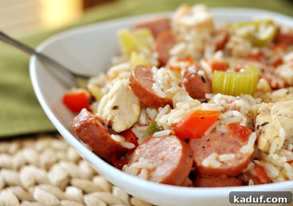 A pristine white dish overflowing with a vibrant chicken and sausage jambalaya, showcasing tender chicken pieces, sliced sausage, and colorful vegetables mixed with fluffy rice.