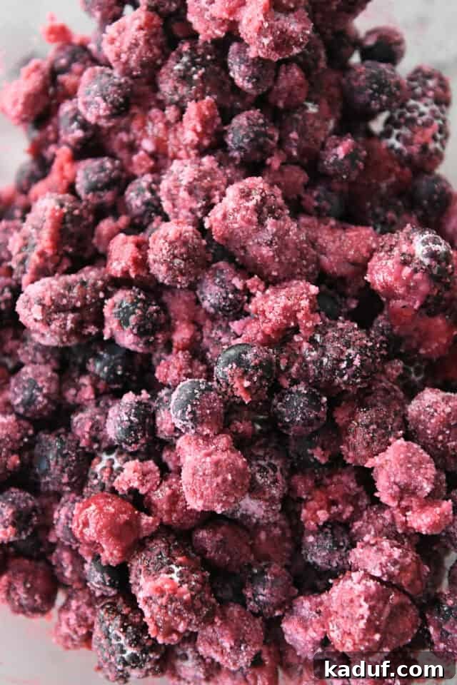 Berry Trio Bliss 3 Frozen raspberries, blueberries, and blackberries are artfully mixed with granulated sugar and cornstarch in a large bowl, ready for the pie filling.