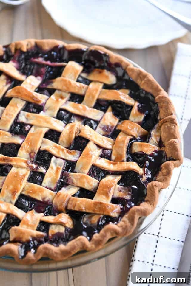 Berry Trio Bliss 7 A perfectly baked, lattice-topped triple berry pie in a glass pie plate, showcasing its golden crust and bubbling, vibrant filling.
