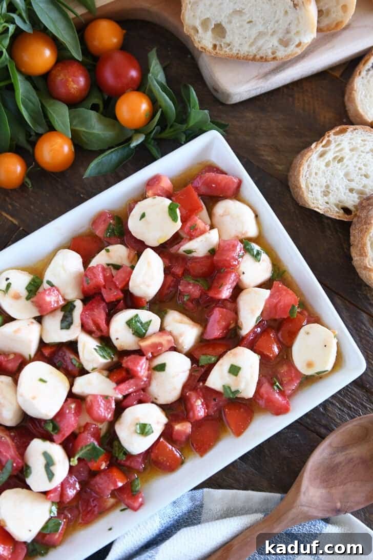 Effortless Caprese Salad 2 Top down view of a a white dish full of tomato mozzarella caprese salad.