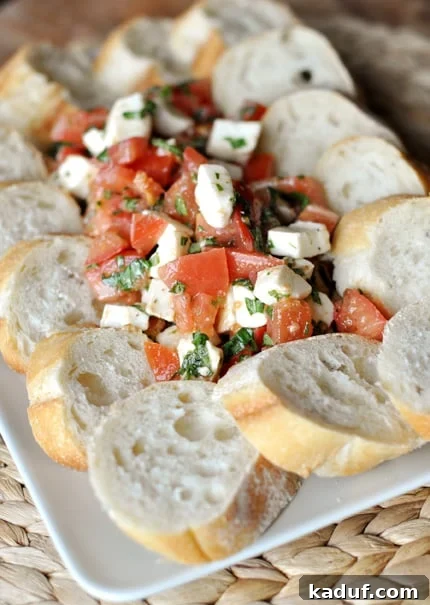 Effortless Caprese Salad 8 A caprese salad in the middle of a white plate with slices of focaccia bread around the salad.