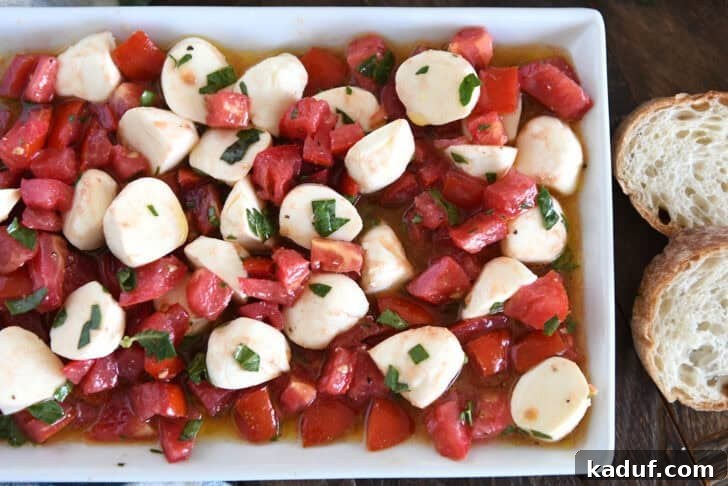 Effortless Caprese Salad 5 A white dish full of tomato mozzarella caprese salad.