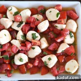 A white dish full of tomato mozzarella caprese salad.