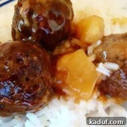 A close-up of delicious pineapple meatballs ready to be served, highlighting their glossy sauce and pineapple chunks.