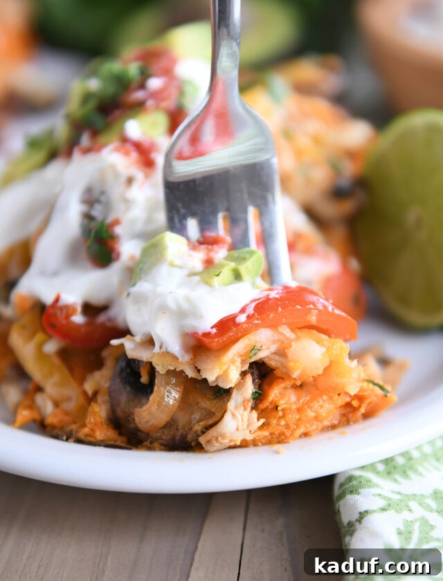 Fork taking bite of sweet potato with bell peppers, mushrooms, sour cream and avocados.