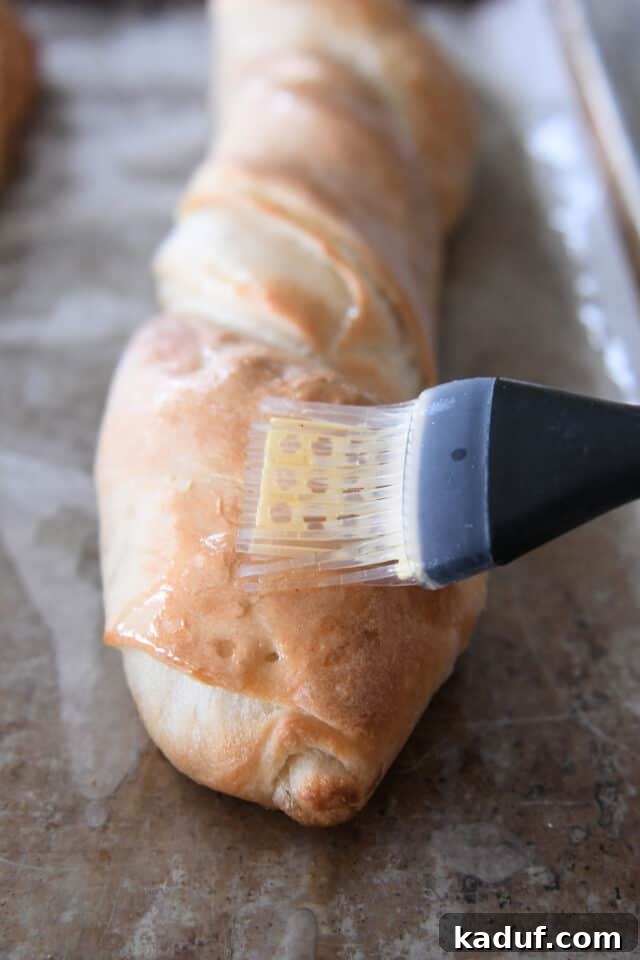Effortless Twisted Croissant French Bread 12 Brushing butter on croissant french bread with pastry brush.