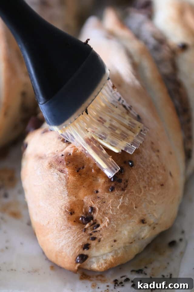 French Chocolate Swirl Bread 12 Brushing melted butter over the tops of freshly baked, golden-brown loaves of French bread, enhancing their flavor and shine.