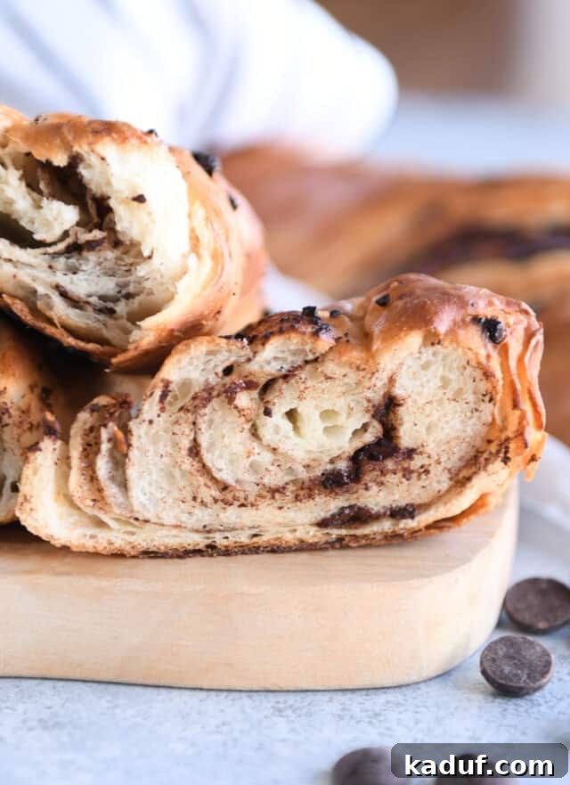 French Chocolate Swirl Bread 14 A cross-section of a baked loaf of chocolate croissant French bread, revealing its beautiful layers and melted chocolate pockets.