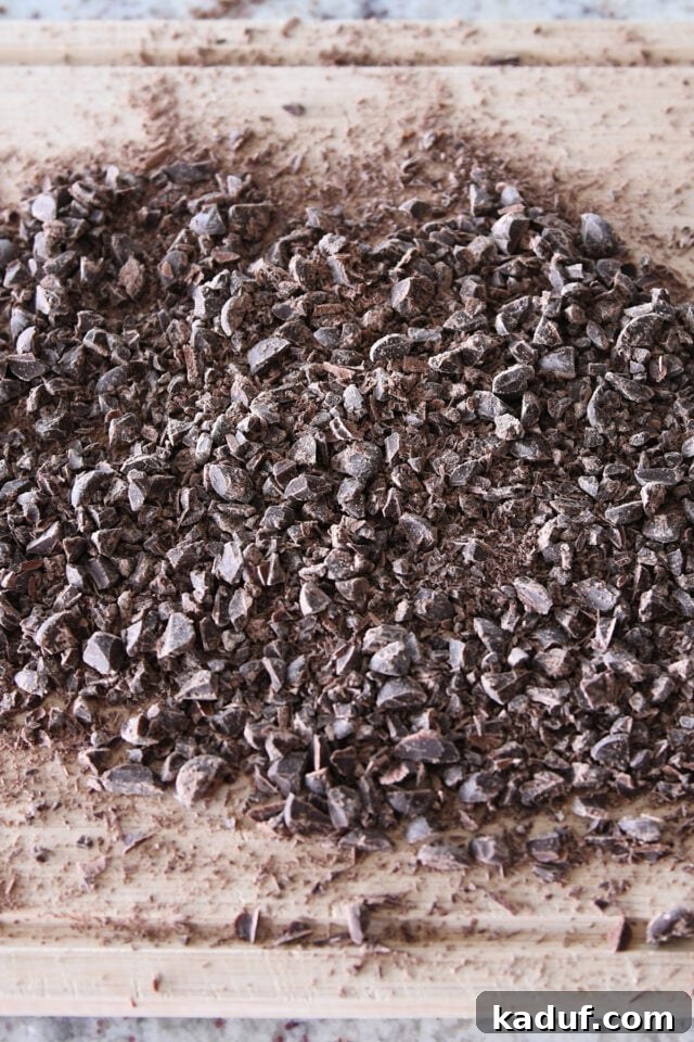 French Chocolate Swirl Bread 7 Coarsely chopped dark chocolate, ready to be incorporated into the bread dough, on a wooden cutting board.