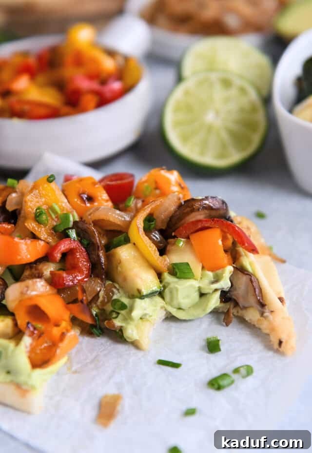 Garden Harvest Flatbread with Avocado Cream 8 Bite taken out of flatbread with creamy avocado sauce and roasted vegetables.