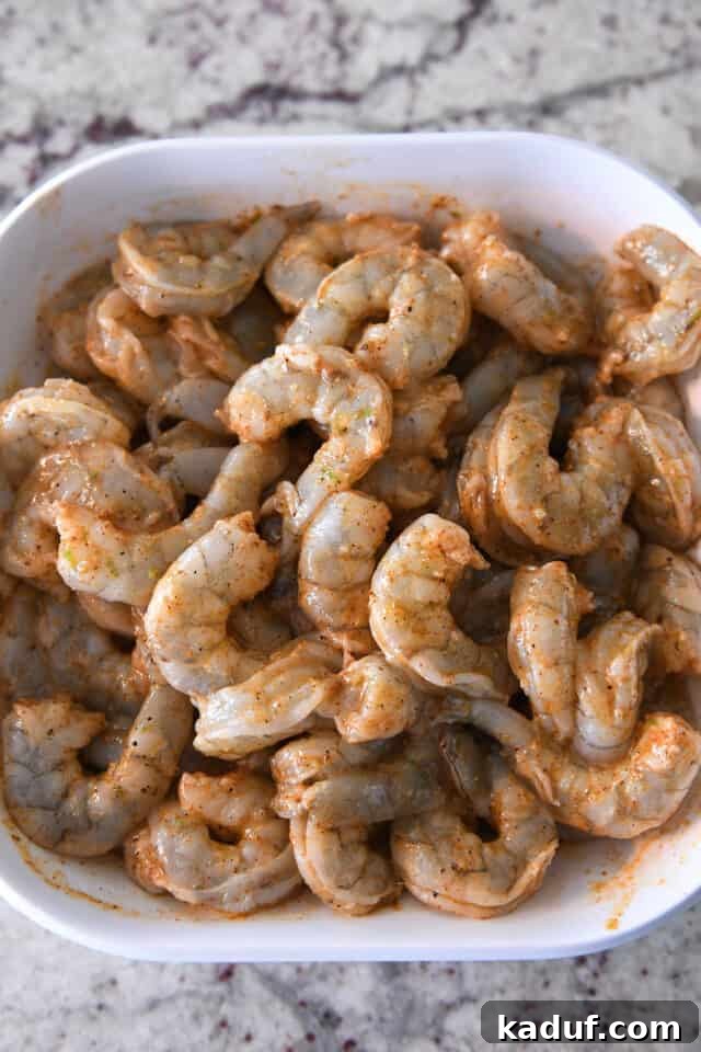 Zesty Chile Lime Shrimp Tacos 5 White bowl with uncooked shrimp in lime zest and seasonings.