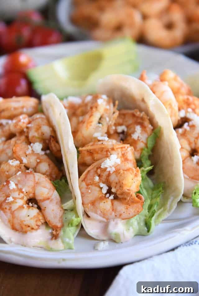 Zesty Chile Lime Shrimp Tacos 7 Three shrimp tacos on white ridged plate.