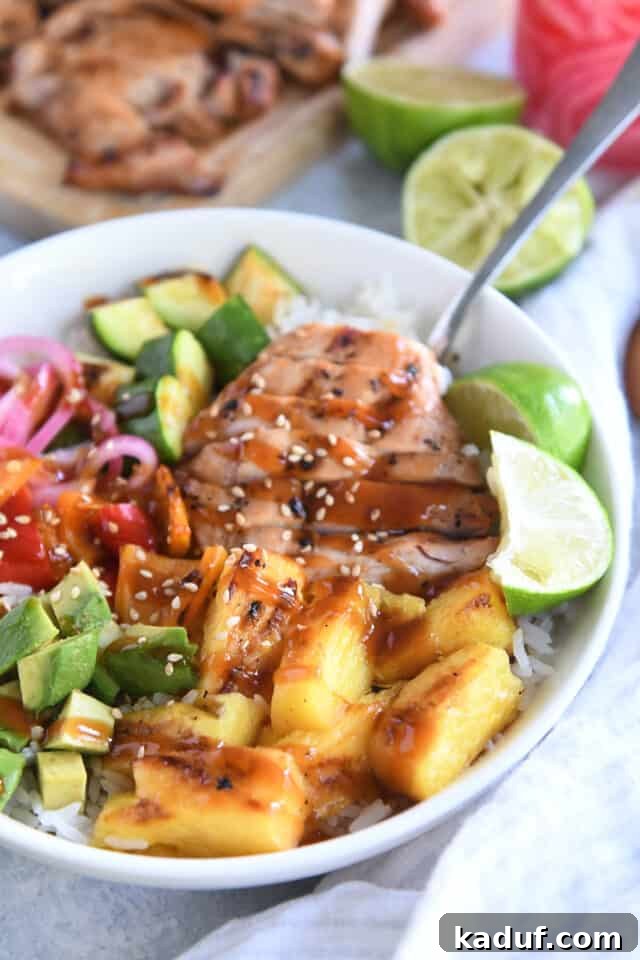 Tropical Chicken Teriyaki Power Bowl 7 A vibrant white bowl generously filled with succulent slices of grilled chicken, bright green fresh limes, sweet golden pineapple, creamy avocado, and colorful bell peppers and zucchini, embodying a perfect balance of healthy and delicious.