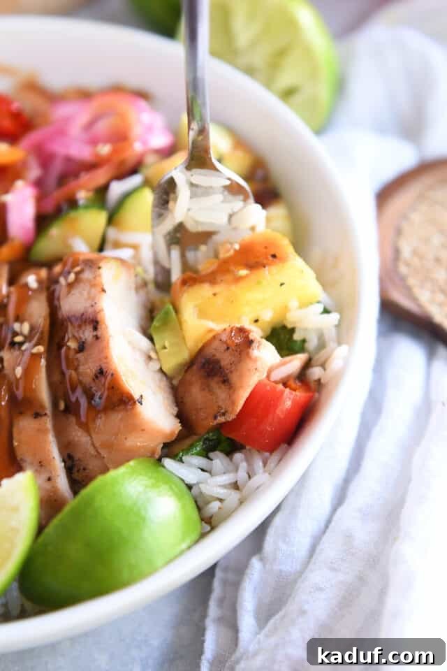 Tropical Chicken Teriyaki Power Bowl 8 A fork poised to take a bite, capturing a perfect morsel of grilled pineapple, tender chicken, and crisp red pepper, highlighting the delicious textures and flavors of the Hawaiian teriyaki bowl.
