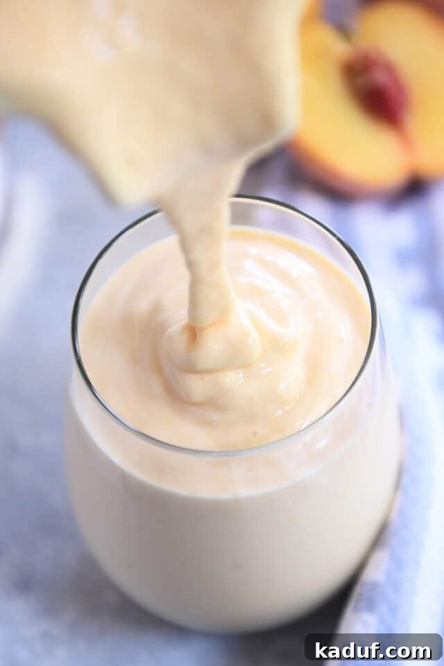 Golden Sunrise Peach Protein Smoothie 4 Smoothie being poured into a tall glass, showcasing its creamy and thick texture, ready to be enjoyed.