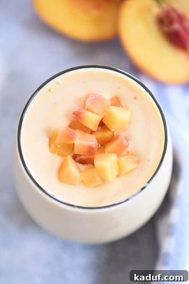 Golden Sunrise Peach Protein Smoothie 5 Top-down view of a Sunrise Peach Orange Protein Smoothie in a glass, garnished with diced fresh peaches, inviting you to take a sip.