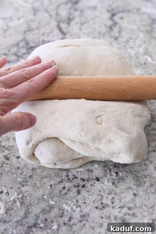 Flaky Cinnamon Croissant Swirl 14 A rolling pin working on the tri-folded dough to achieve a perfect 12-inch square for cutting.