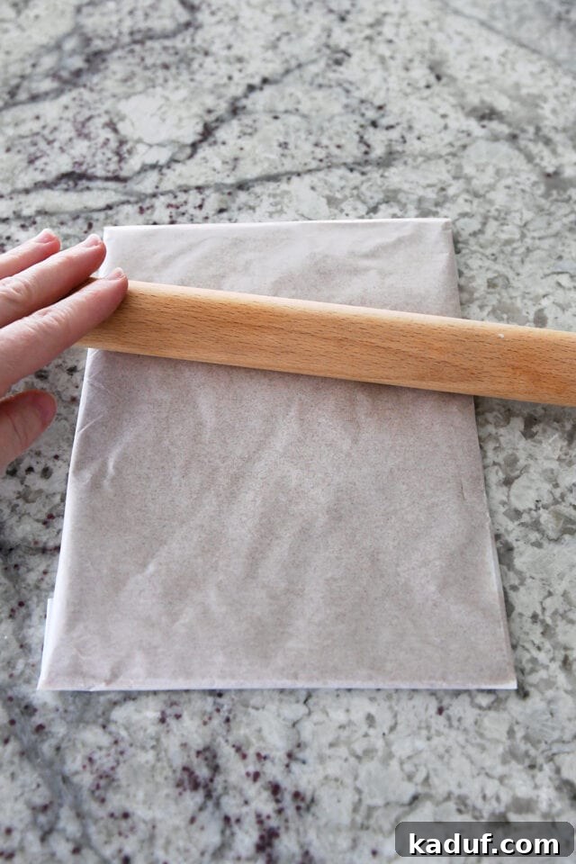 Flaky Cinnamon Croissant Swirl 4 A rolling pin gently pressing the cinnamon sugar butter packet within parchment paper to create an even, thin sheet.