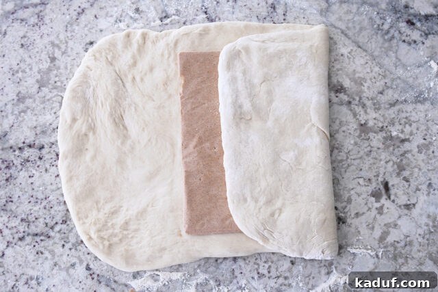 Flaky Cinnamon Croissant Swirl 6 Cinnamon sugar butter packet perfectly centered on the rolled-out French bread dough, ready for folding.