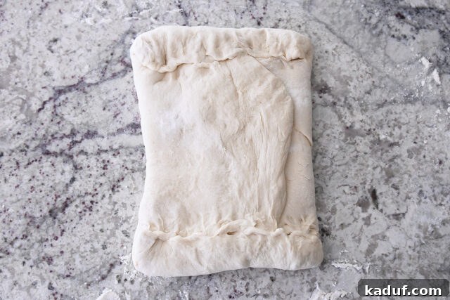Flaky Cinnamon Croissant Swirl 8 The butter packet fully encased in dough with edges pinched and sealed, demonstrating secure lamination.