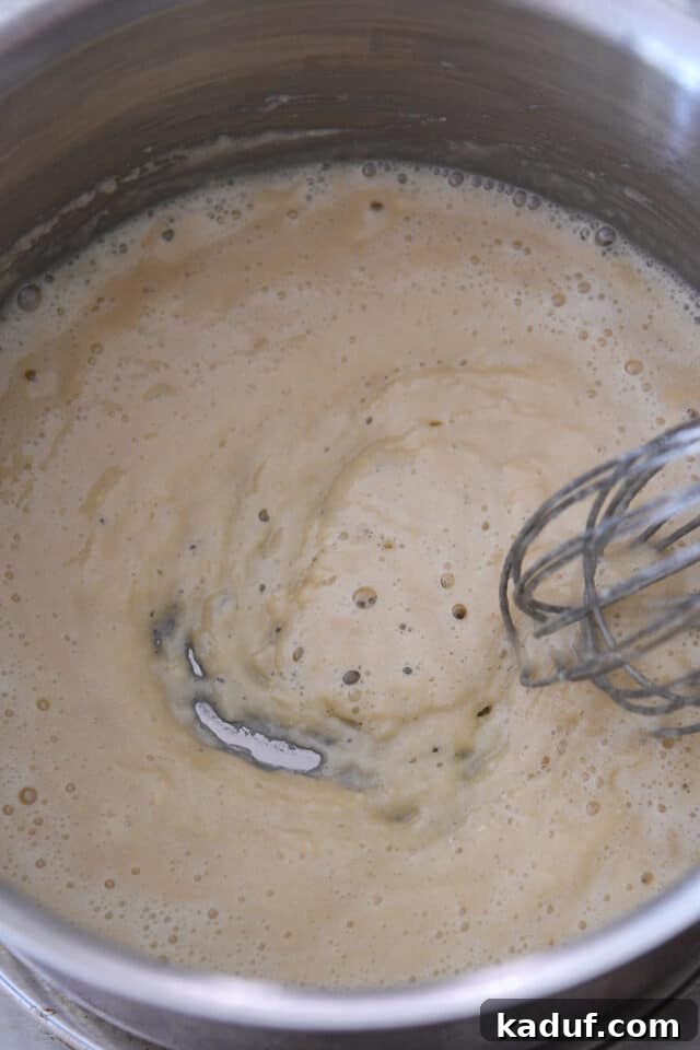 Cooking butter and flour to create a roux in a saucepan with a whisk.