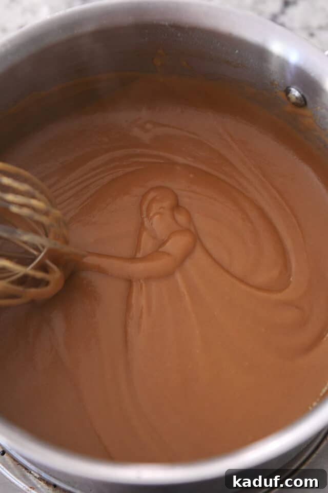 A whisk swirling in a saucepan, revealing smooth, thickening gravy.