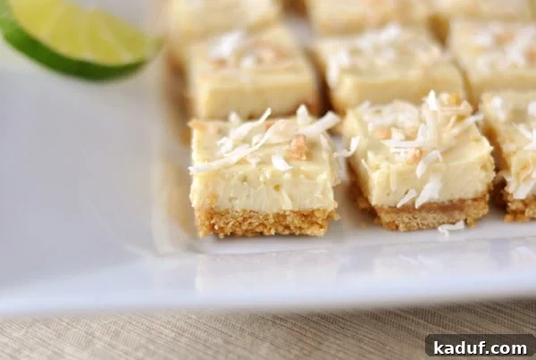 Zesty Key Lime Delights 2 White platter with toasted coconut-topped key lime bars cut into small squares, ready to be served.
