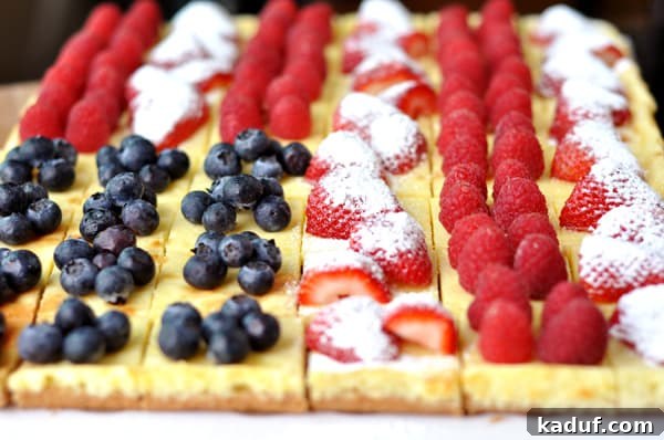 Vibrant Fruit Cheesecake Centerpiece 3 Individual cheesecake squares, each meticulously decorated with berries to form a miniature American flag pattern. A close-up view showcasing the intricate fruit arrangement on the creamy white cheesecake.