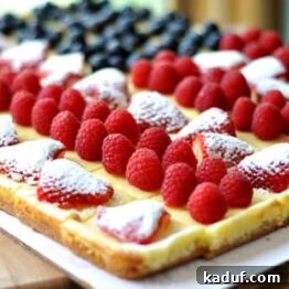 A beautifully presented slice of Festive Fruited Cheesecake Flag, showcasing the layers of shortbread crust, creamy cheesecake, and fresh berry toppings arranged in a flag pattern.