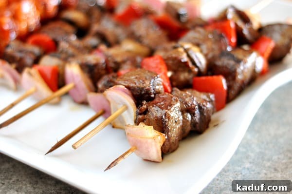 Juicy Steak and Vibrant Vegetable Skewers 3 White platter full of grilled beef and vegetable kebabs, showcasing the perfectly cooked meat and vegetables.
